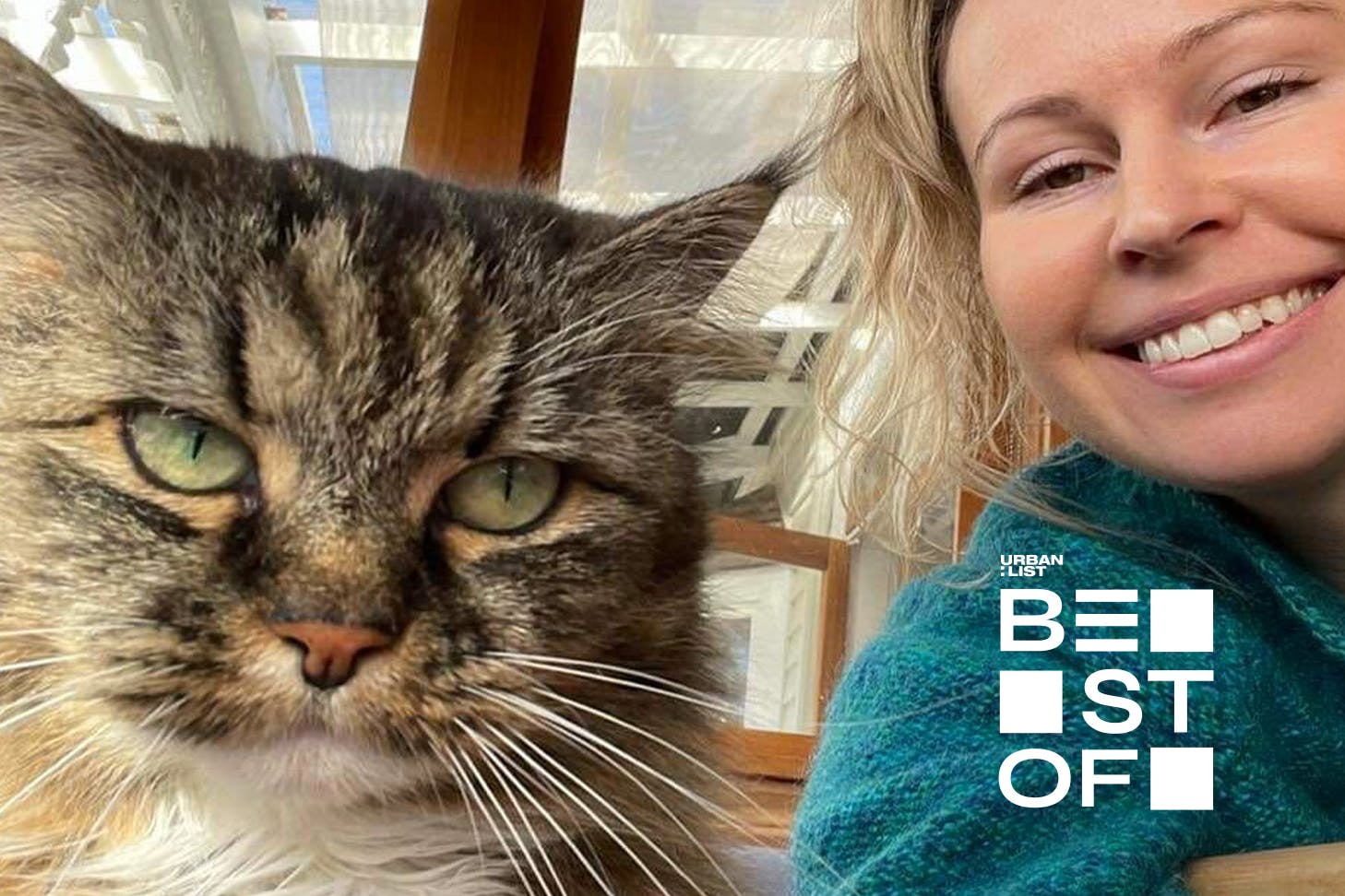 A woman smiles and takes a selfie with her cat